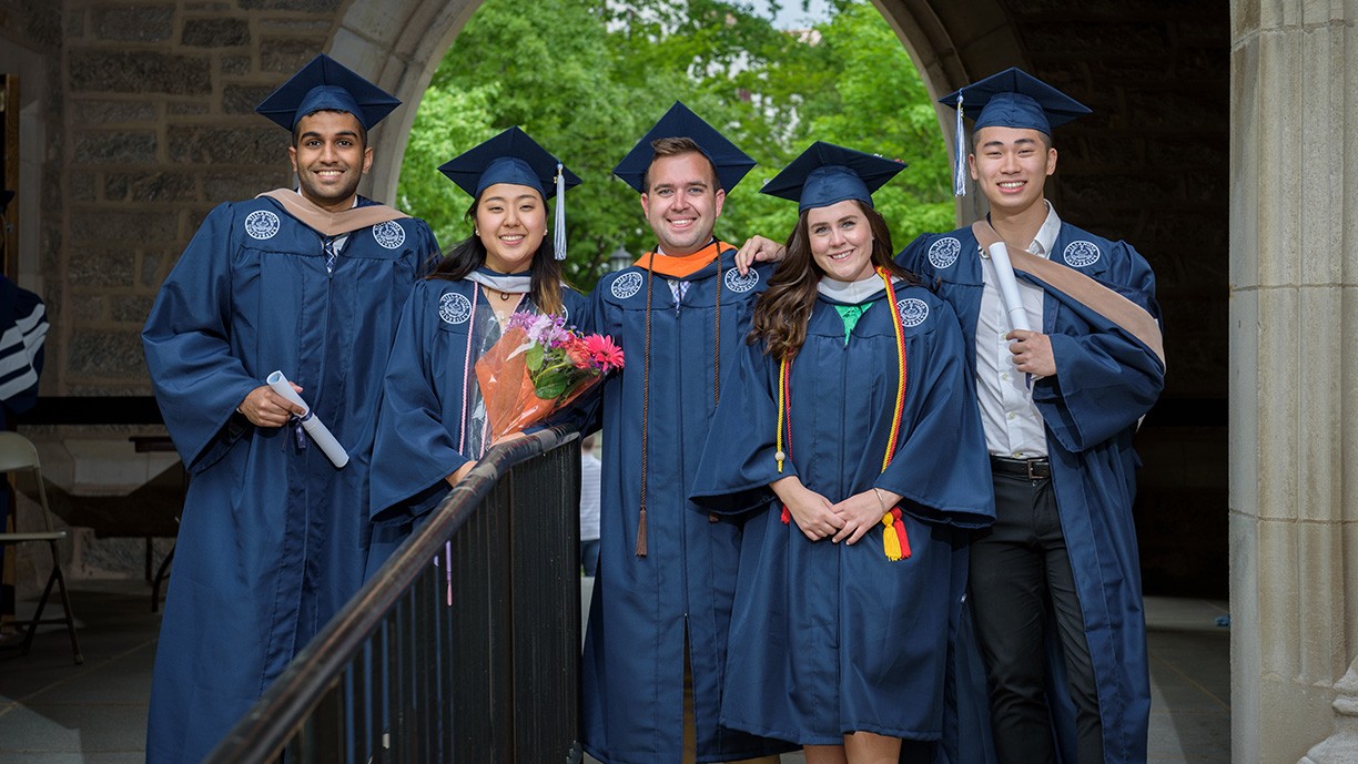 5 ר alumni in graduation cap and gowns on campus